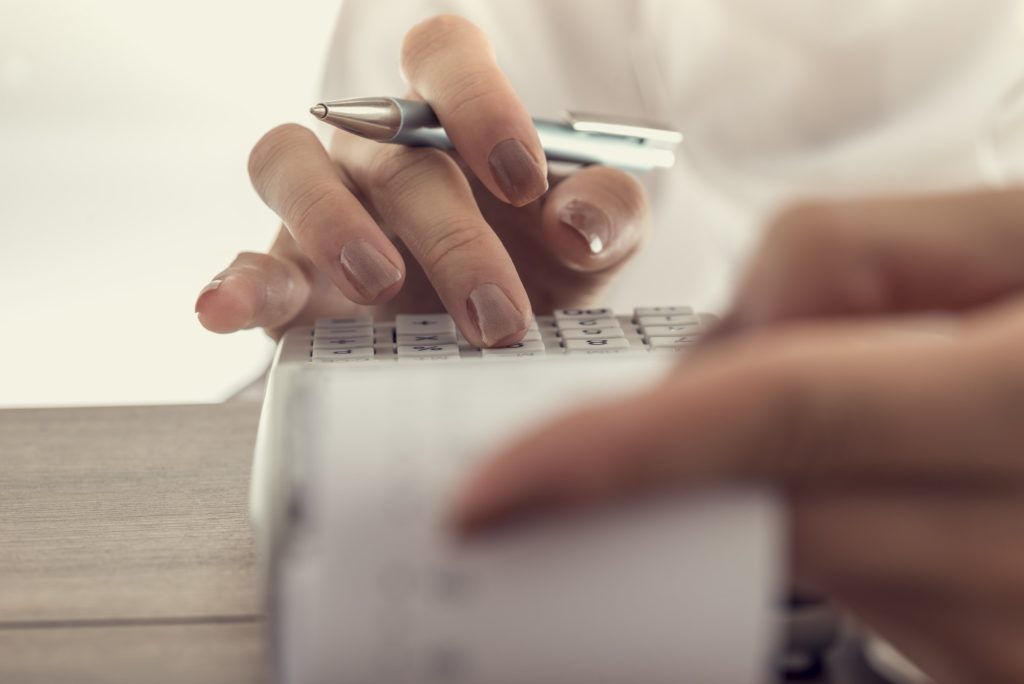Closeup low angle view of a woman using a manual adding machine
